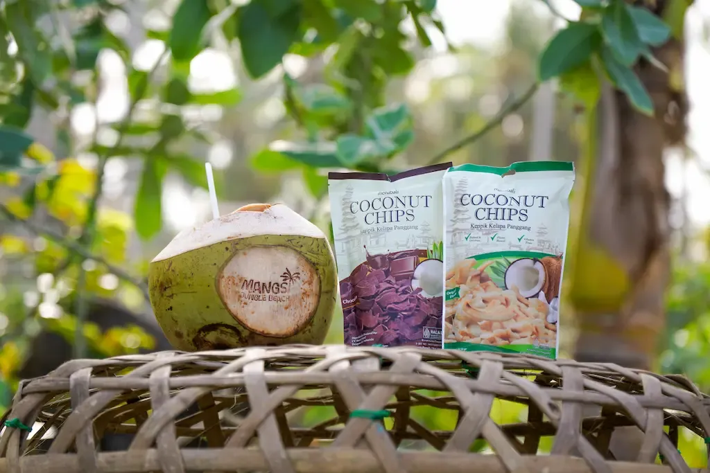 Packs of Merubali Coconut Chips on a woven tray outdoors